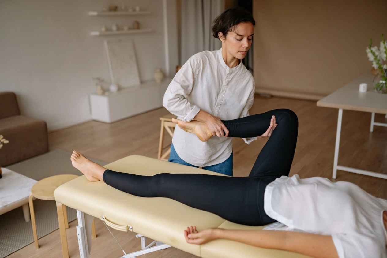 Home health care specialist stretching the leg of a client on a table.